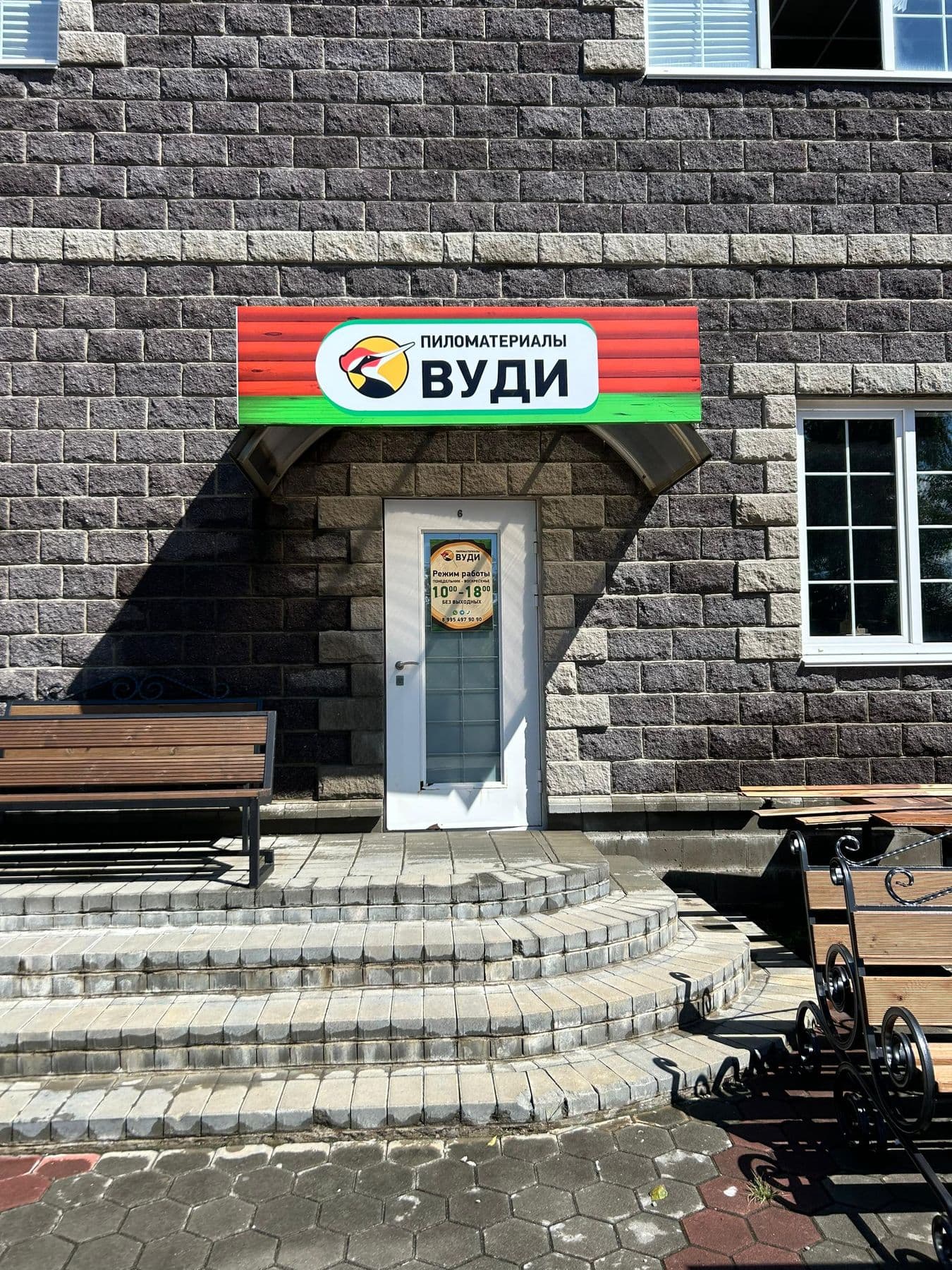 Вход в склад-магазин ВУДИ во Владивостоке: вывеска «Пиломатериалы ВУДИ», ступени и садовые скамейки из дерева